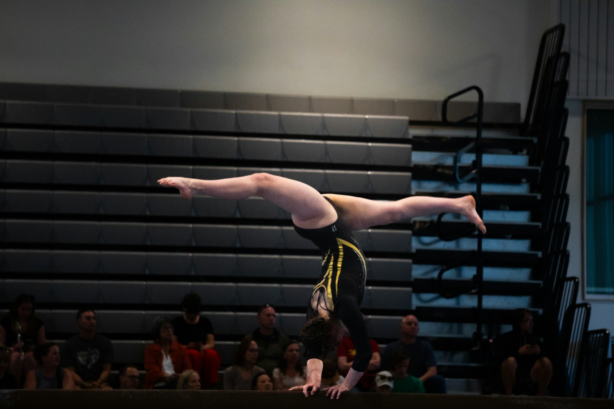 A gymnast holding a handstand on a balance beam
